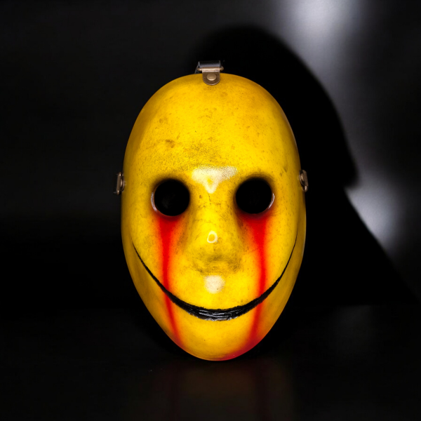 A yellow smiley face mask with blood running from the eyes.