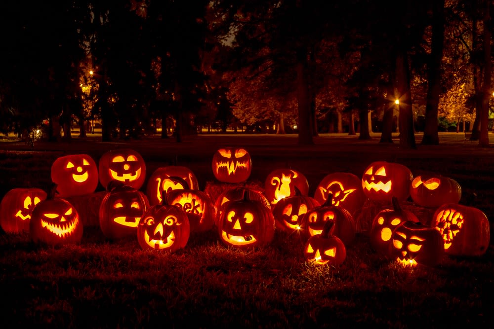 Carved jack-o'-lanterns glowing outdoors at night
