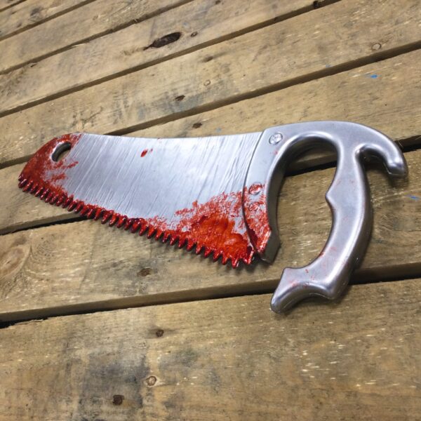 A PU foam replica bone saw covered in blood.