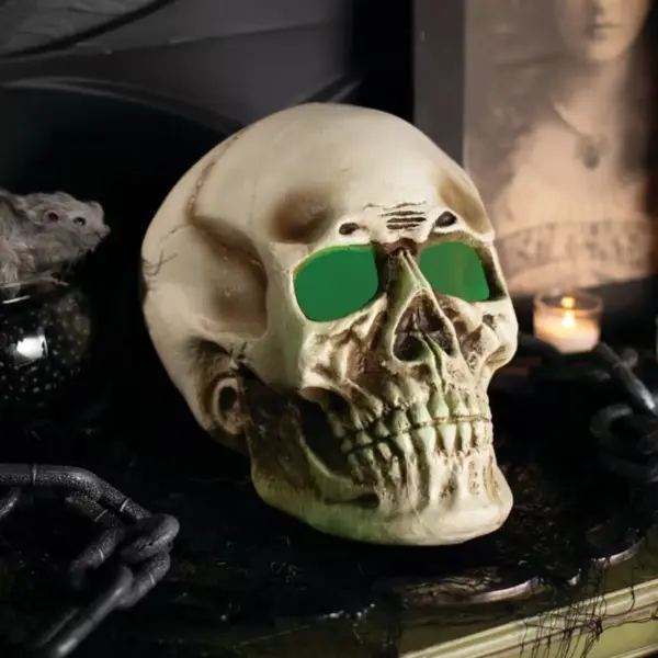 Ein plastischer Halloween-Deko-Schädel mit grün leuchtenden Augen.